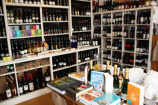 Weinregale in der lesezeit, davor ein Tisch mit Büchern und Sekt